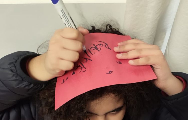 تمرین spelling کلمات جدید توسط دانش آموزان روی کاغذ و بر روی سرشان 1