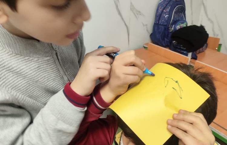 تمرین spelling کلمات جدید توسط دانش آموزان روی کاغذ و بر روی سرشان 3