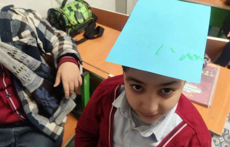 تمرین spelling کلمات جدید توسط دانش آموزان روی کاغذ و بر روی سرشان 4